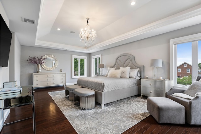 bedroom with a chandelier, dark wood finished floors, a tray ceiling, and recessed lighting