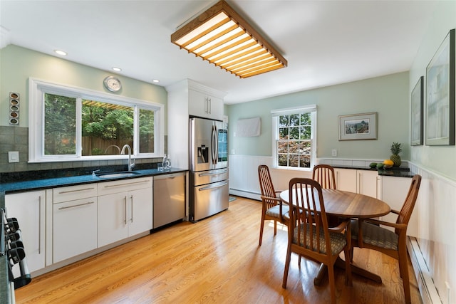 50 Burnside Dr, Hastings-On-Hudson, NY 10706 - kitchen with stainless steel appliances, baseboard heating, wainscoting, white cabinetry, and dark countertops