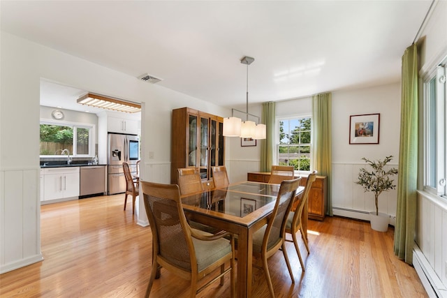 50 Burnside Dr, Hastings-On-Hudson, NY 10706 - dining space with a baseboard heating unit, light wood-type flooring, healthy amount of natural light, wainscoting, and a decorative wall