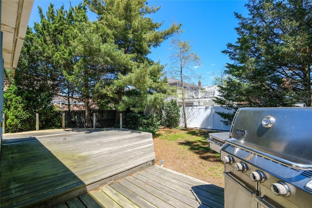 deck with area for grilling and a fenced backyard