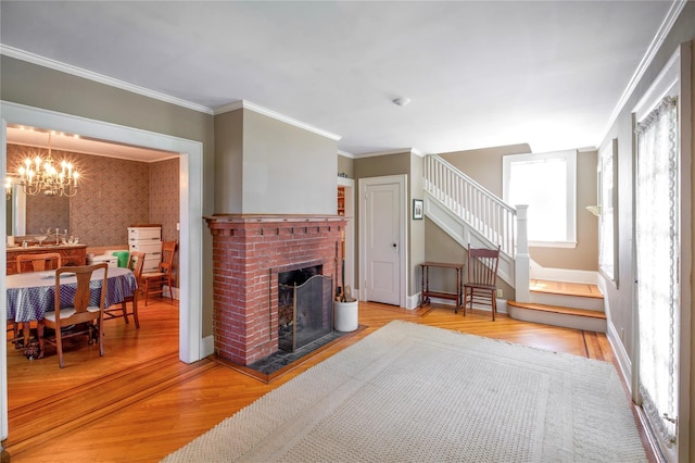 living room with plenty of natural light, stairway, wood finished floors, a fireplace, and crown molding