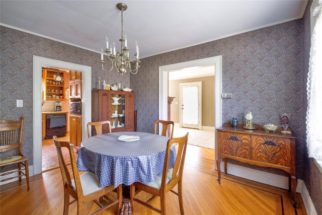 dining room featuring wood finished floors, a chandelier, and crown molding