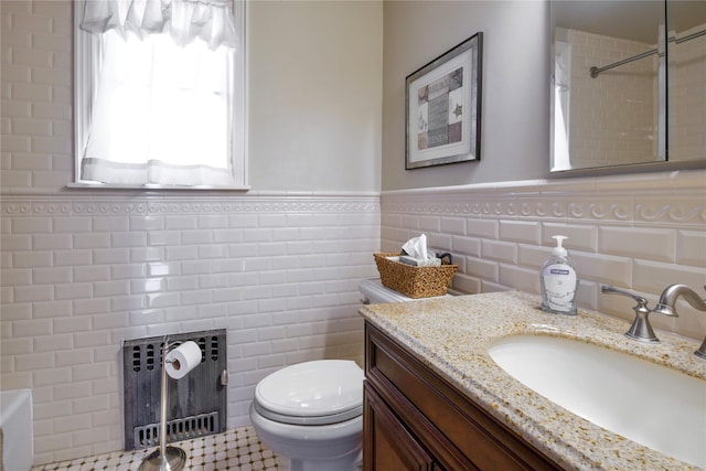 full bath featuring toilet, a shower, tile walls, vanity, and wainscoting