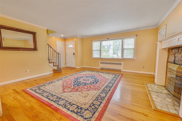 1652 Baker Ave, Merrick, NY 11566 - foyer featuring radiator heating unit, a stone fireplace, light wood-type flooring, stairs, and ornamental molding