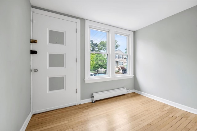 entryway featuring a baseboard heating unit, light wood-style flooring, and baseboards