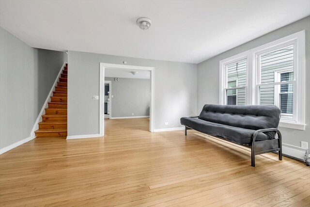 sitting room featuring light wood finished floors, stairway, and baseboards