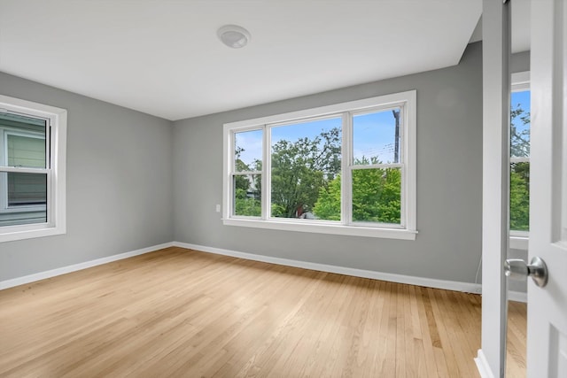 spare room featuring baseboards and light wood-style floors