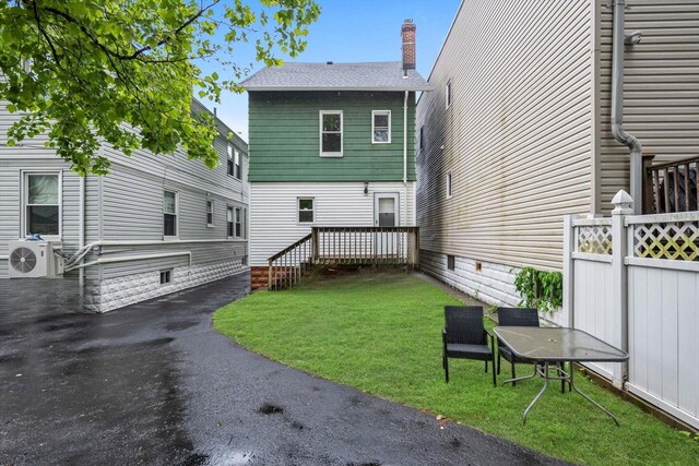 back of property featuring a wooden deck, a chimney, and a shingled roof
