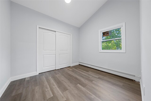 545 Granny Rd, Medford, NY 11763 - unfurnished bedroom with baseboard heating, vaulted ceiling, wood finished floors, baseboards, and a closet