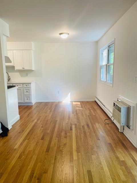 82 Demarest Ave Unit 15, West Nyack, NY 10994 - unfurnished living room with light wood-style flooring, a baseboard radiator, and baseboards