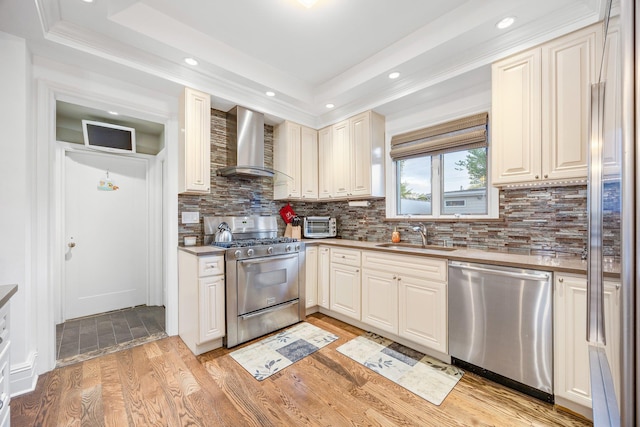 1 3rd Pl, Bellmore, NY 11710 - kitchen with stainless steel appliances, wall chimney range hood, a sink, a raised ceiling, and light wood-type flooring
