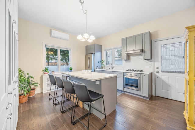 1 3rd Pl, Bellmore, NY 11710 - kitchen featuring appliances with stainless steel finishes, a wall mounted air conditioner, gray cabinetry, a sink, and a chandelier