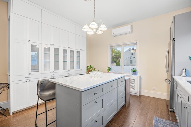 1 3rd Pl, Bellmore, NY 11710 - kitchen featuring gray cabinets, an AC wall unit, wood finished floors, baseboards, and a chandelier