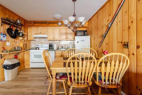 76 Highlands Dr Unit C2, Hunter, NY 12442 - kitchen featuring white appliances, under cabinet range hood, a chandelier, light wood-style floors, and wood walls