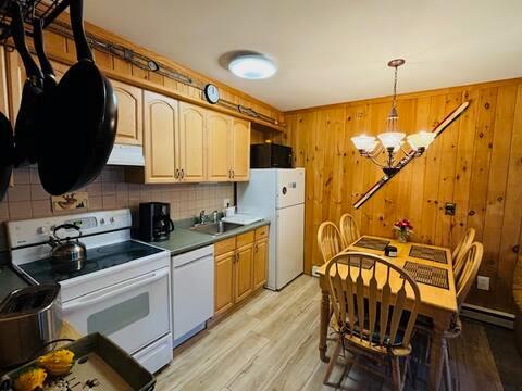 76 Highlands Dr Unit C2, Hunter, NY 12442 - kitchen with white appliances, a chandelier, decorative backsplash, under cabinet range hood, and light wood-type flooring