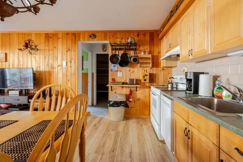 76 Highlands Dr Unit C2, Hunter, NY 12442 - kitchen with electric stove, under cabinet range hood, light wood-type flooring, wood walls, and tasteful backsplash
