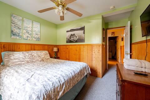 76 Highlands Dr Unit C2, Hunter, NY 12442 - bedroom featuring a wainscoted wall, carpet flooring, wooden walls, and a ceiling fan