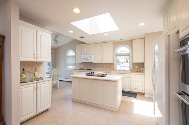 745 Willow Rd, Franklin Square, NY 11010 - kitchen featuring white appliances, a skylight, tasteful backsplash, light countertops, and baseboard heating