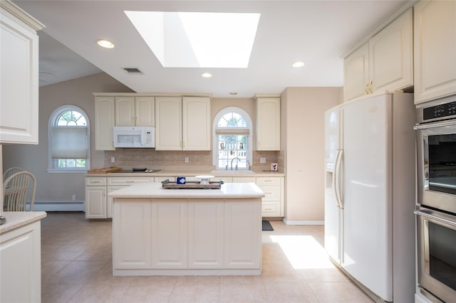 745 Willow Rd, Franklin Square, NY 11010 - kitchen with white appliances, a baseboard heating unit, a sink, a skylight, and backsplash
