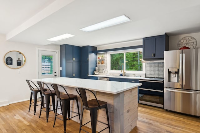 162 Forest Hill Dr, Kingston, NY 12401 - kitchen featuring stainless steel appliances, blue cabinetry, a breakfast bar area, and decorative backsplash