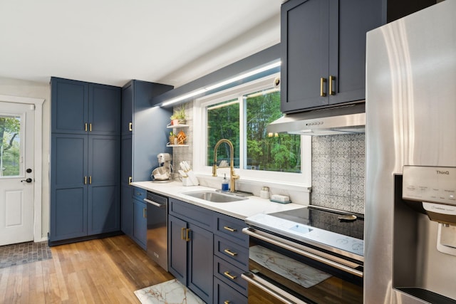 162 Forest Hill Dr, Kingston, NY 12401 - kitchen with appliances with stainless steel finishes, under cabinet range hood, a sink, blue cabinets, and plenty of natural light