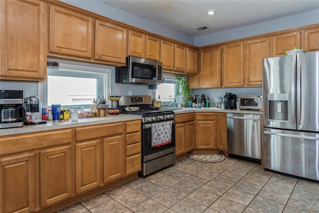 161 W Walnut St, Long Beach, NY 11561 - kitchen featuring appliances with stainless steel finishes, light countertops, light tile patterned floors, brown cabinets, and recessed lighting