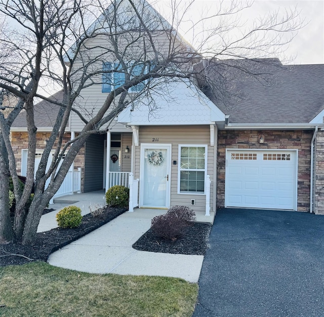 211 Pond Cir, Mount Sinai, NY 11766 - view of front facade with stone siding, a garage, covered porch, and asphalt driveway