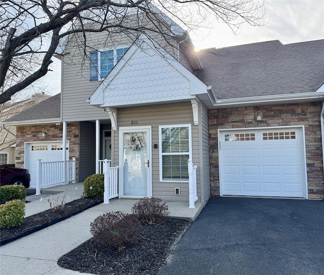 211 Pond Cir, Mount Sinai, NY 11766 - view of front of property with a garage, stone siding, asphalt driveway, and roof with shingles