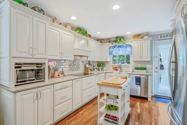8 Emerald Ct, Moriches, NY 11955 - kitchen featuring stainless steel appliances, custom exhaust hood, white cabinets, backsplash, and light wood-style floors