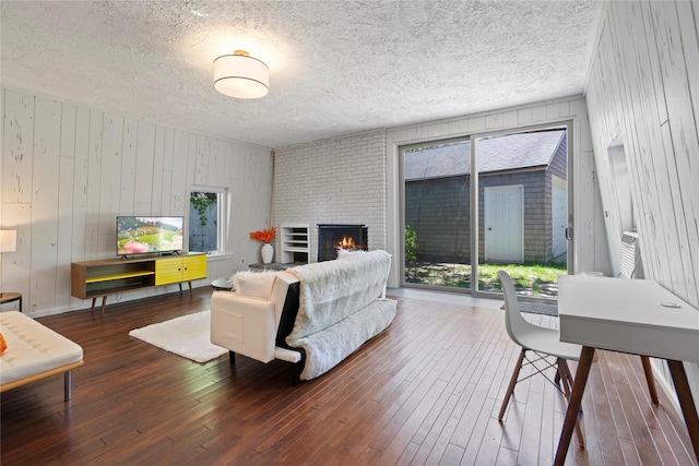 55 W End Ave, East Quogue, NY 11942 - living area featuring hardwood / wood-style floors, wooden walls, a fireplace, and a textured ceiling