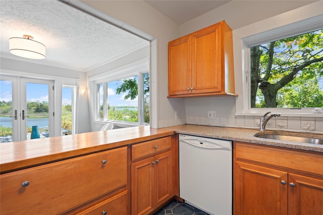 55 W End Ave, East Quogue, NY 11942 - kitchen with white dishwasher, a sink, french doors, a textured ceiling, and brown cabinetry