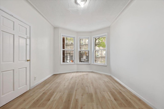 unfurnished bedroom featuring light wood-style floors, baseboards, and a textured ceiling
