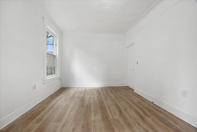 unfurnished room with light wood-type flooring, crown molding, and baseboards