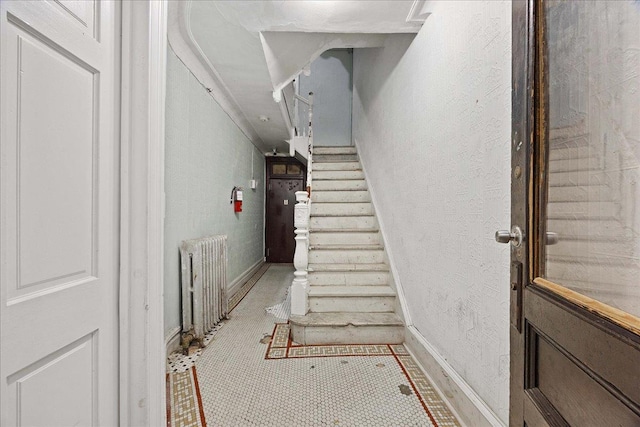 stairway featuring radiator heating unit, baseboards, and tile patterned flooring