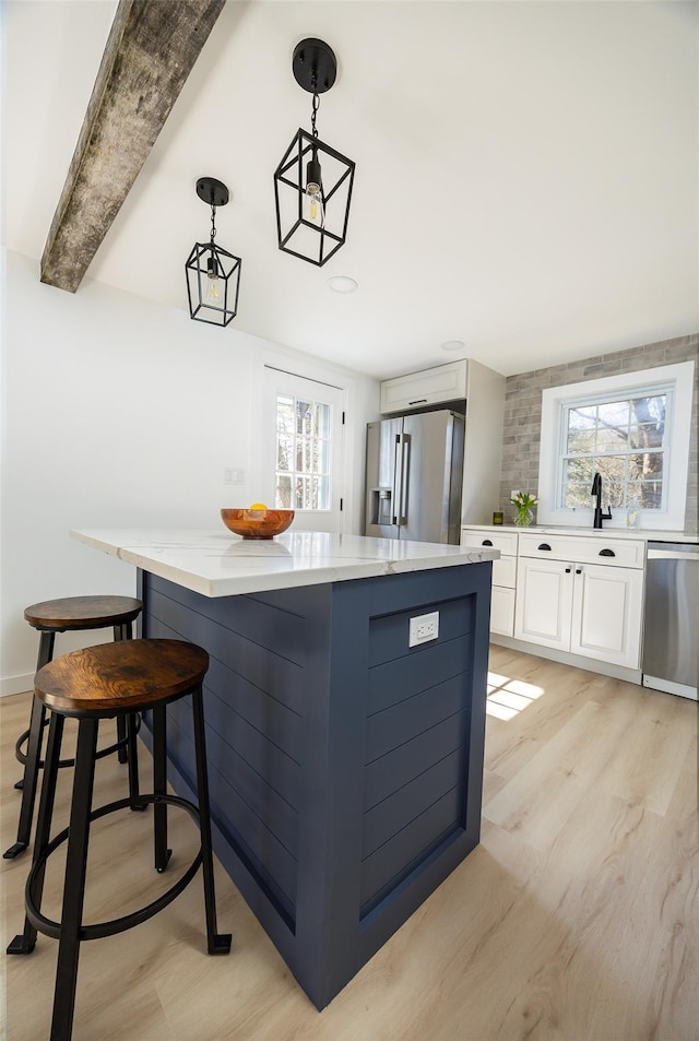 3 Holt Rd, Red Hook, NY 12571 - kitchen featuring stainless steel appliances, a center island, light wood finished floors, white cabinets, and a kitchen bar