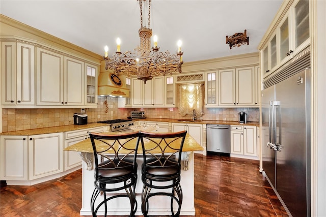 186-31 Radnor Rd, Jamaica Estates, NY 11432 - kitchen featuring appliances with stainless steel finishes, cream cabinetry, a sink, and a chandelier