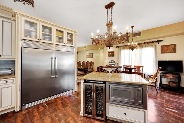 186-31 Radnor Rd, Jamaica Estates, NY 11432 - kitchen with built in appliances, cream cabinetry, beverage cooler, and a chandelier