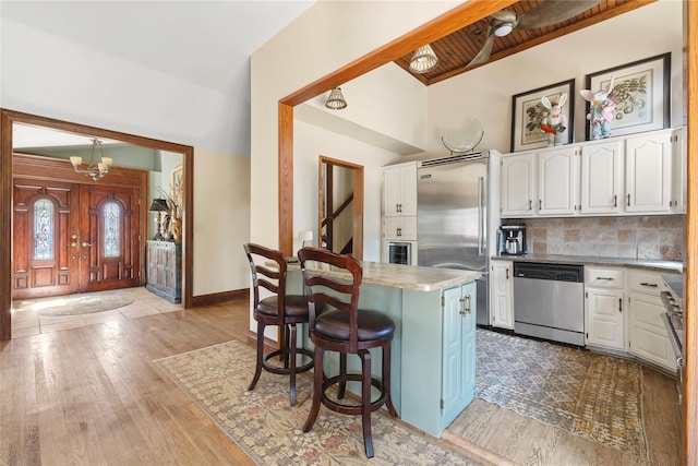 24 Brushwood Ct, East Islip, NY 11730 - kitchen featuring stainless steel appliances, white cabinets, a kitchen bar, wood finished floors, and backsplash