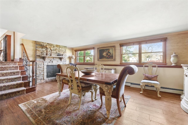 24 Brushwood Ct, East Islip, NY 11730 - dining room featuring a fireplace, stairway, baseboard heating, and light wood finished floors