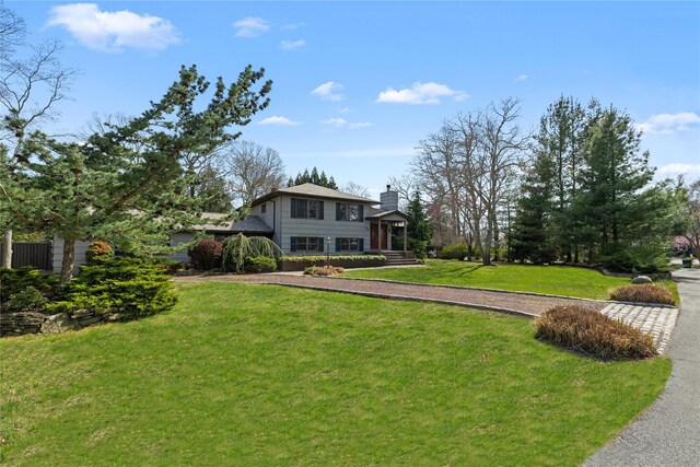 24 Brushwood Ct, East Islip, NY 11730 - view of front facade with a front lawn, a chimney, and driveway