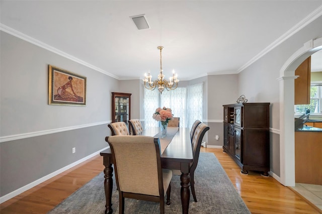 7 Ellbridge Ct, South Setauket, NY 11720 - dining space featuring arched walkways, a chandelier, light wood-type flooring, crown molding, and baseboards