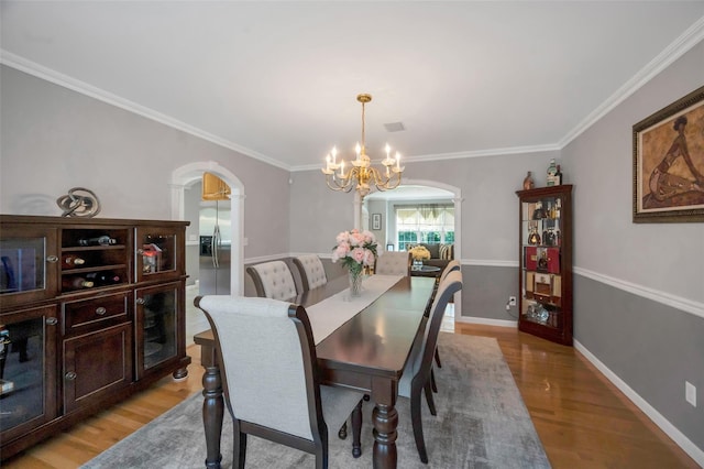 7 Ellbridge Ct, South Setauket, NY 11720 - dining space with arched walkways, a chandelier, light wood-style floors, crown molding, and baseboards