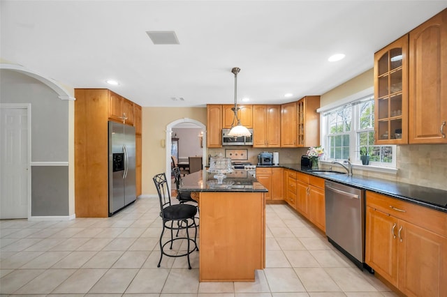 7 Ellbridge Ct, South Setauket, NY 11720 - kitchen with appliances with stainless steel finishes, arched walkways, a breakfast bar, a sink, and a center island