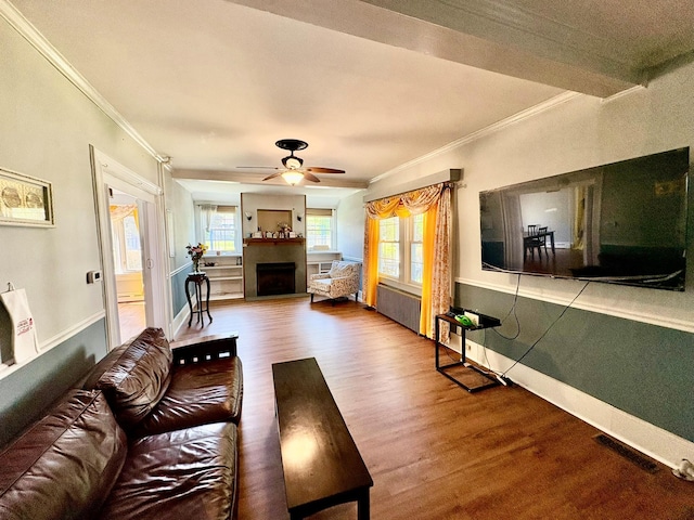 living room with ornamental molding, a fireplace, wood finished floors, a ceiling fan, and baseboards