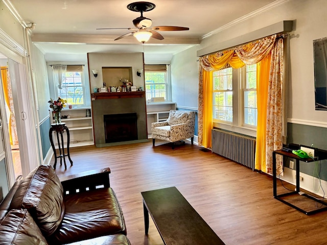 living area featuring radiator heating unit, plenty of natural light, wood finished floors, and crown molding