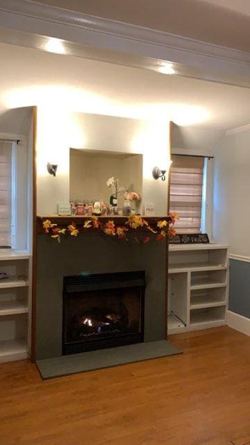 detailed view of a fireplace, ornamental molding, wood finished floors, and baseboards
