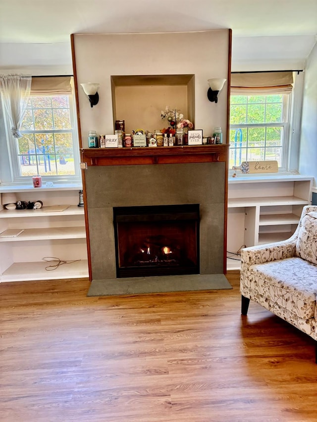 living room with wood finished floors and a warm lit fireplace