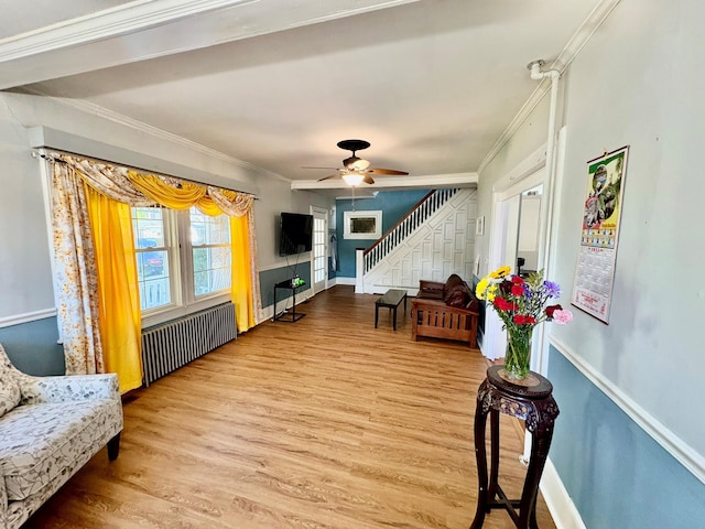 living area featuring radiator heating unit, stairs, ornamental molding, wood finished floors, and a ceiling fan