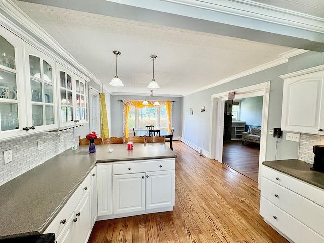 kitchen with crown molding, a peninsula, decorative backsplash, glass insert cabinets, and white cabinetry