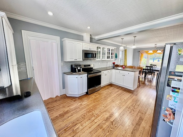kitchen with appliances with stainless steel finishes, a peninsula, light wood-style flooring, white cabinetry, and crown molding